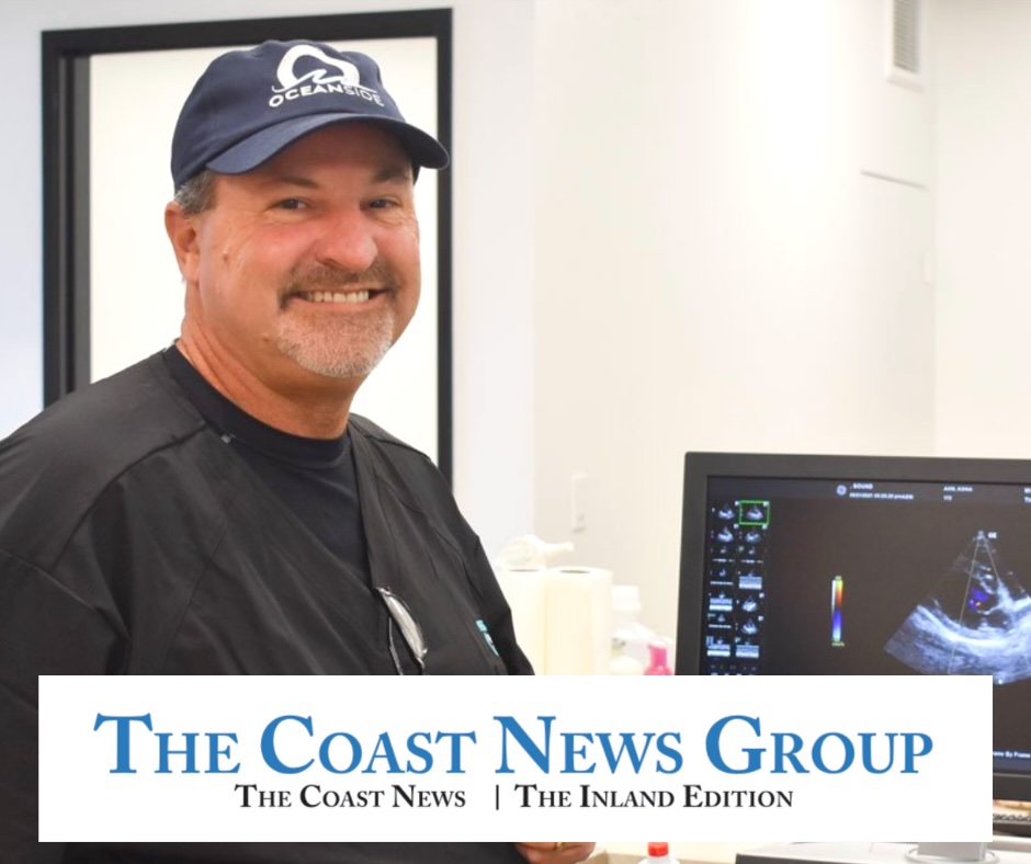 Veterinary team member smiling beside an ultrasound monitor during the grand opening, featured in The Coast News Group — Neighborhood Veterinary Hospital, San Diego, CA