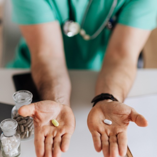 Veterinarian holding out two medication pills with bottles on the desk at Neighborhood Veterinary Hospital in San Diego, CA